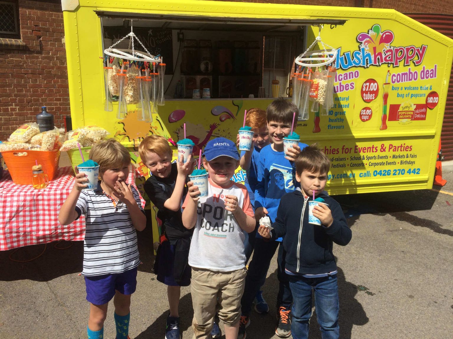 Children with drinks in front of the Slush Happy bus